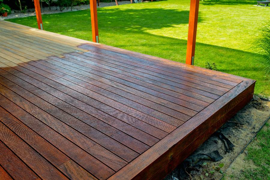 Wooden deck with orange support posts overlooking green lawn and garden area