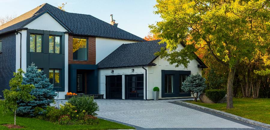 Modern two-story home with white and dark exterior, black roof, and paved driveway